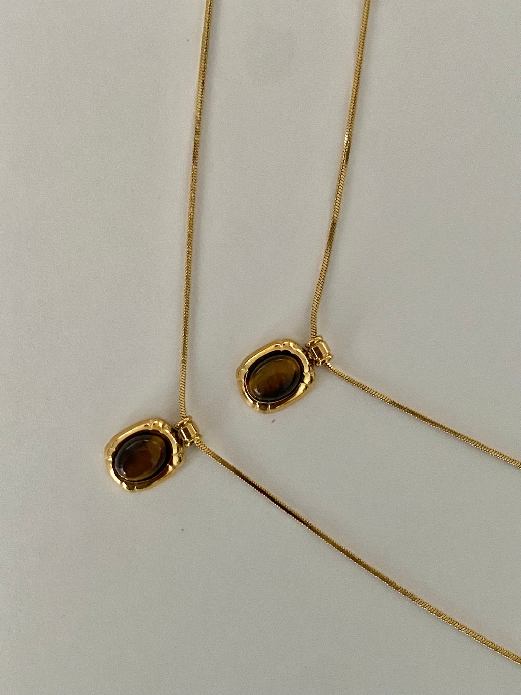 18 ct Gold necklaces with brown gemstones on a light grey background