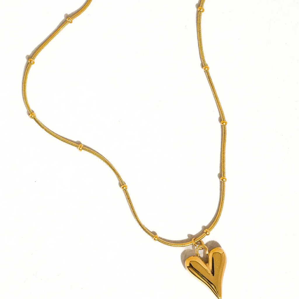 Gold necklace with a heart-shaped pendant on a white background