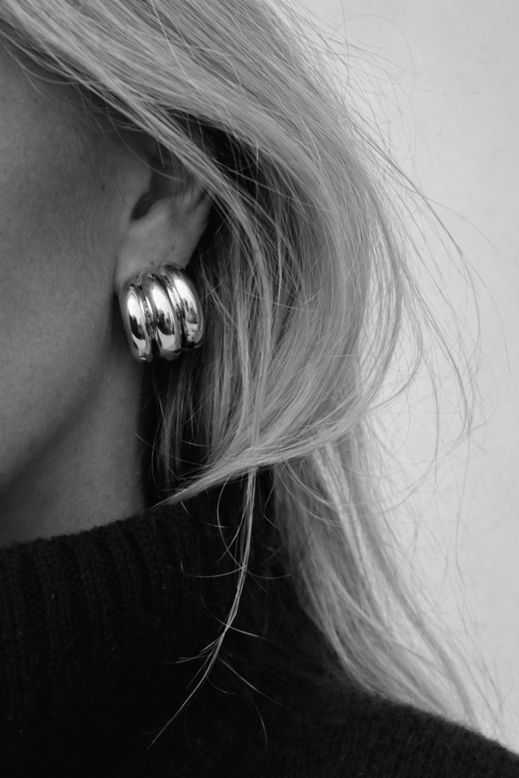 Close-up of an ear wearing a silver hoop earring with blurred background
