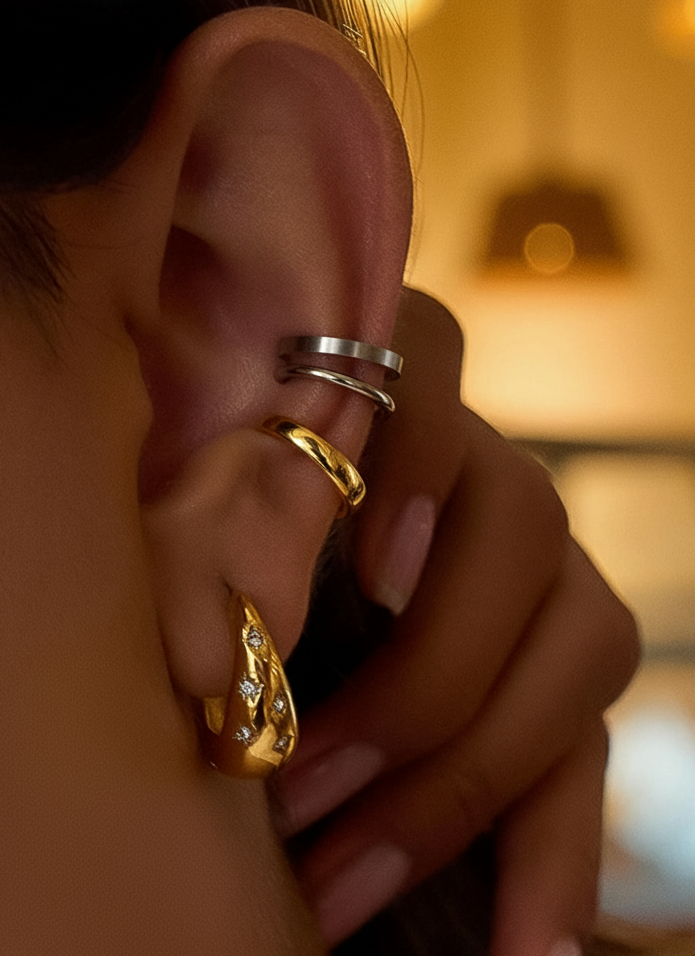 Close-up of an ear with gold and silver ear cuffs and 18ct gold star dome hoops earrings
